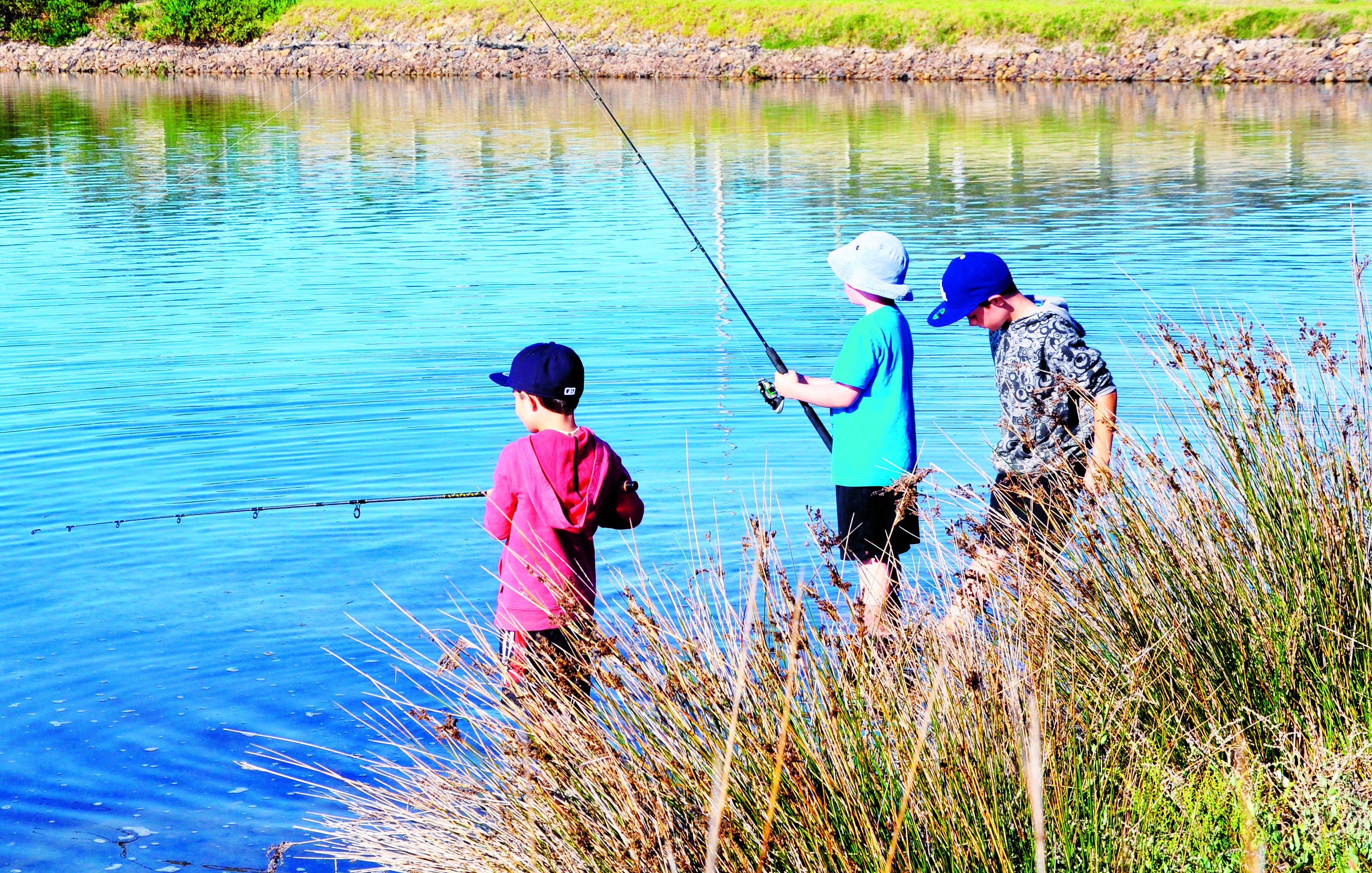 three kids fishing in a lake