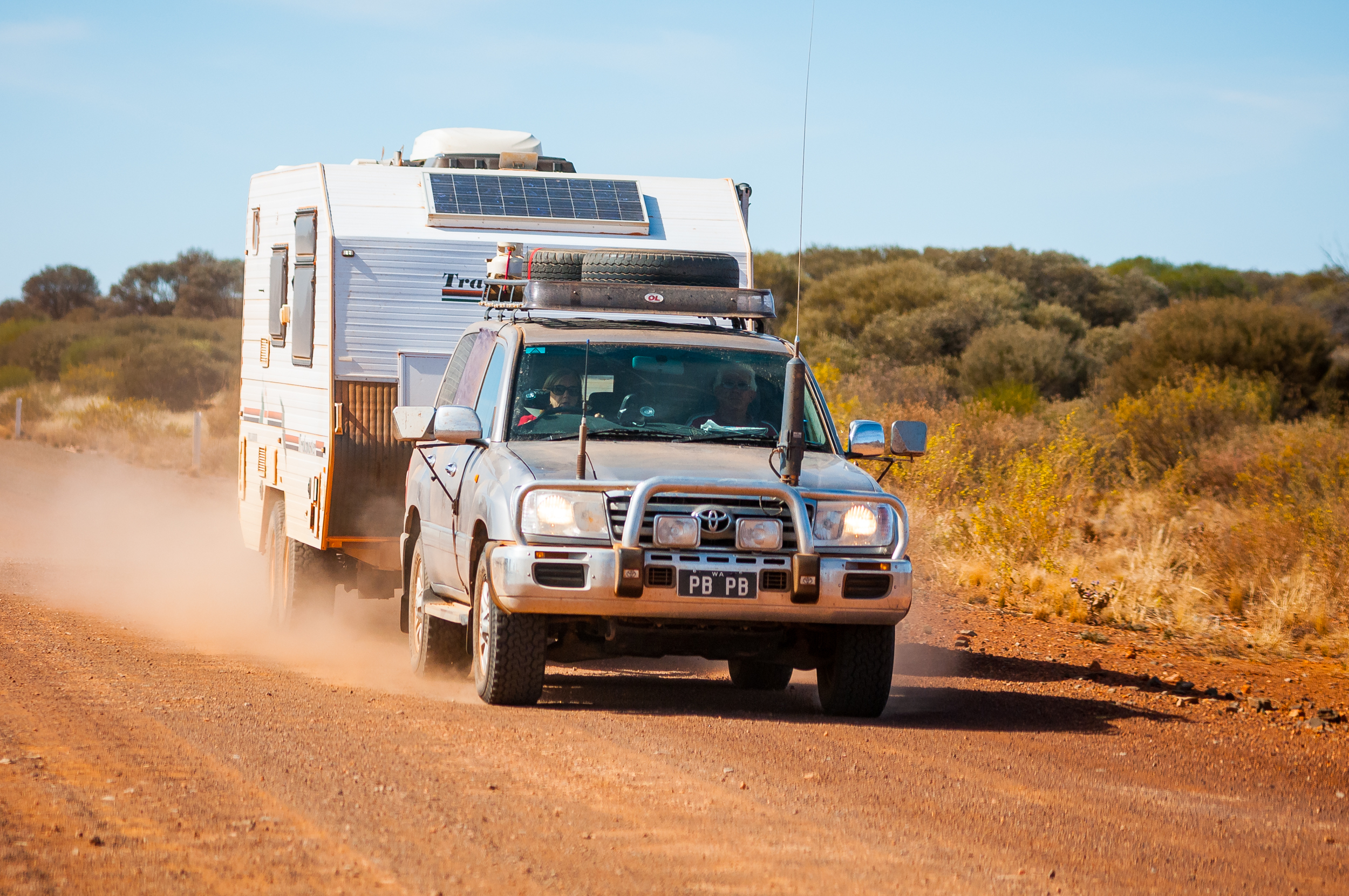 4WD driven by woman towing caravan on a dirt road