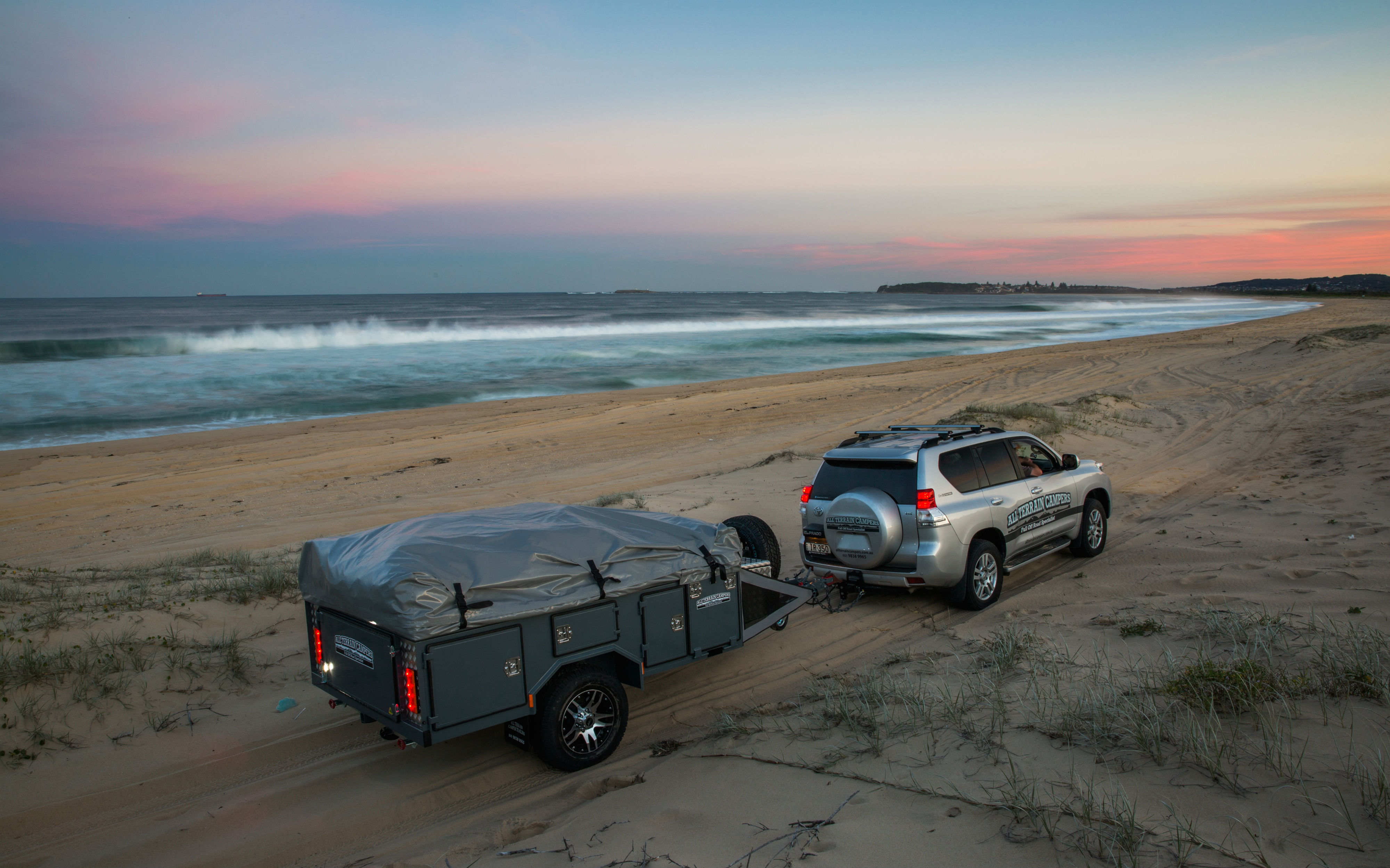 4WD towning a trailer on the beach during dusk