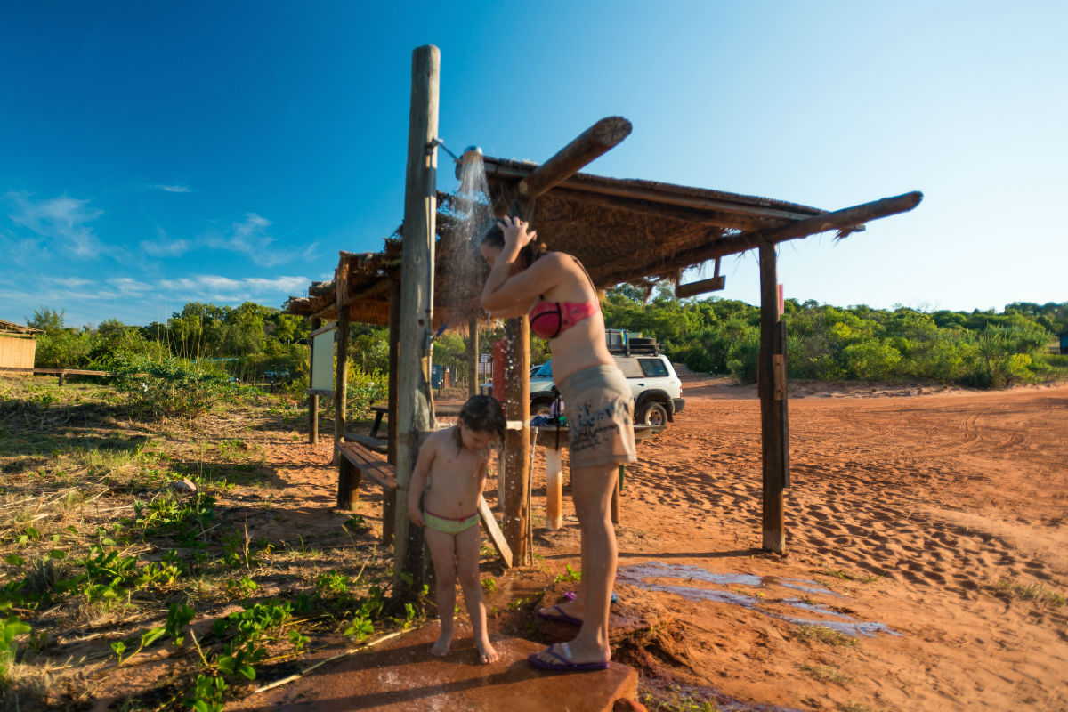 Woman and child using an outdoor shower near the sand
