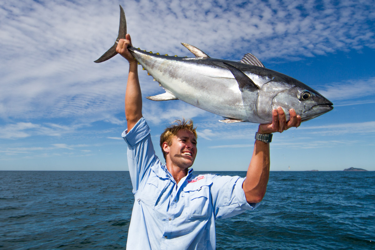 Man holding up a blue fin tuna on boat