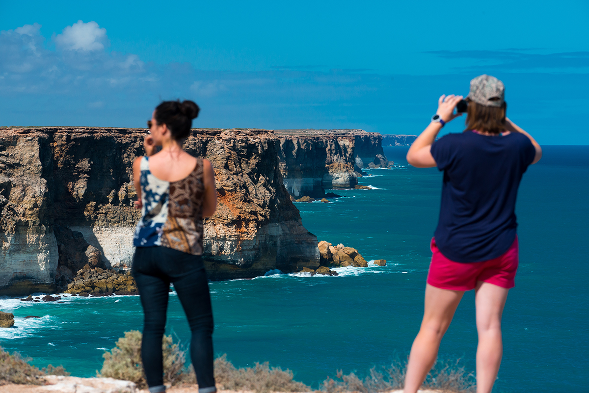 Two-women-taking-photos-of-the-ocean-cliffs