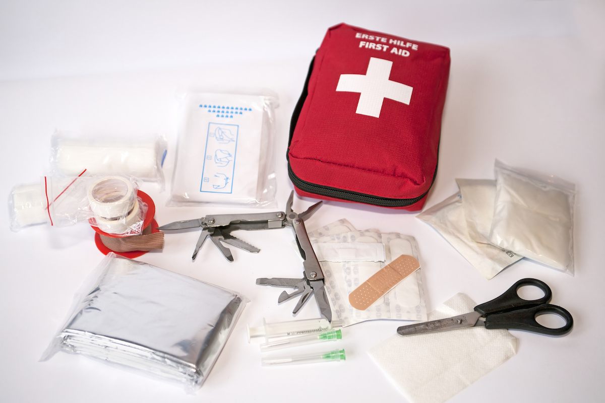 Open first aid kit with bandages, scissors, "triangle scarf", syringe, plaster, knife, tools, gauze, etc