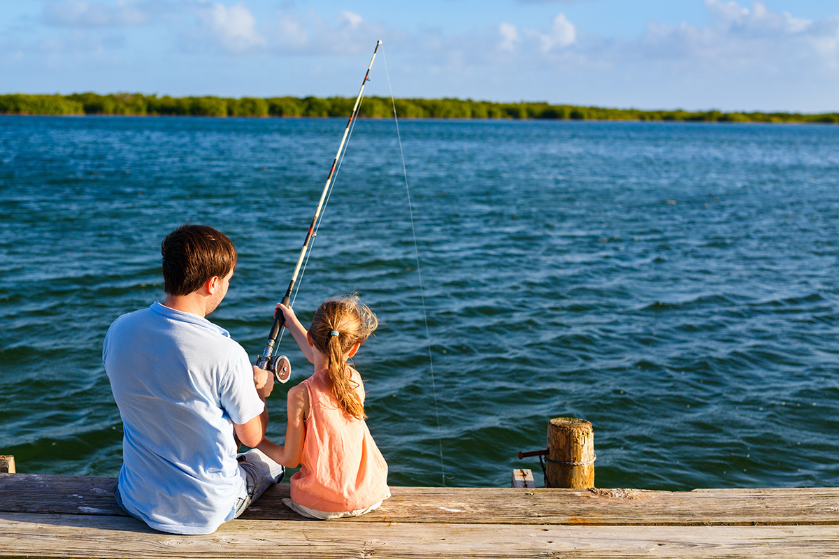 Family father and daughter fishing together from wooden jetty