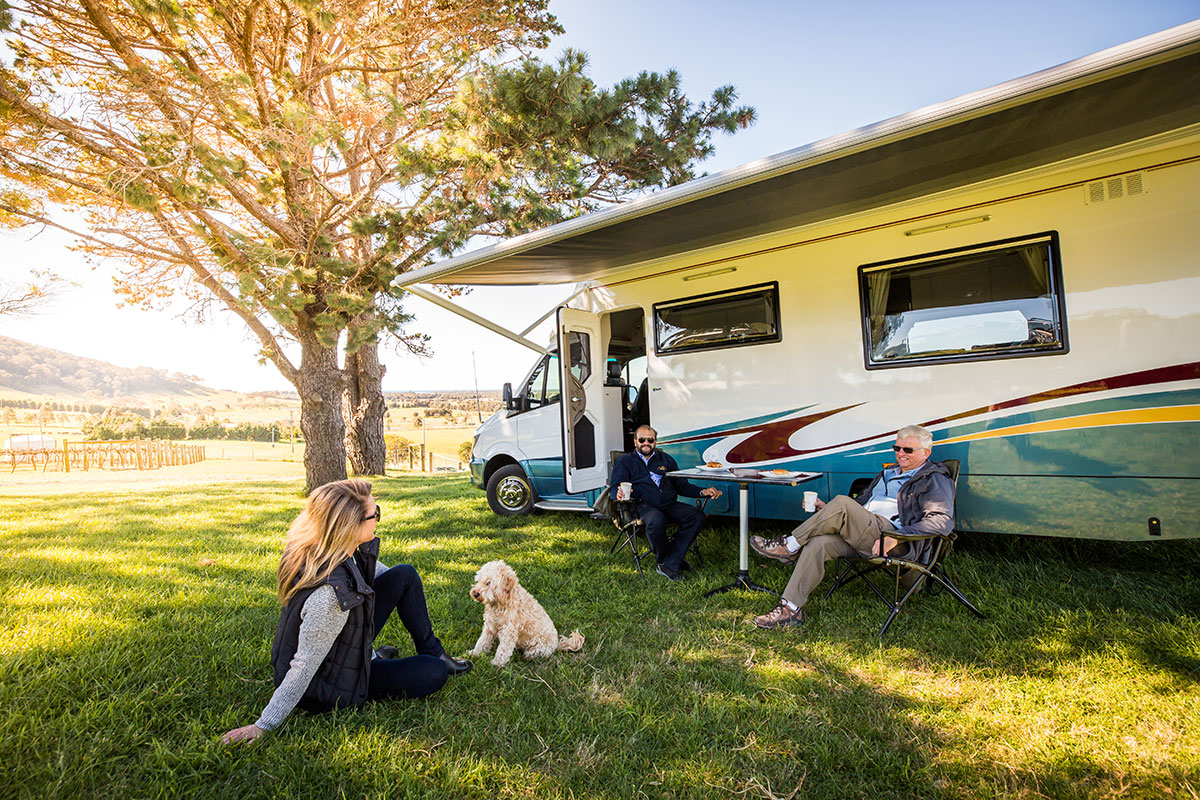 People-sitting-outside-with-a-dog-next-to-a-caravan