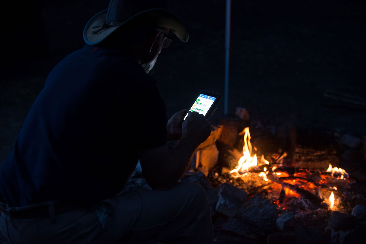 Man-using-his-phone-next-to-a-campfire